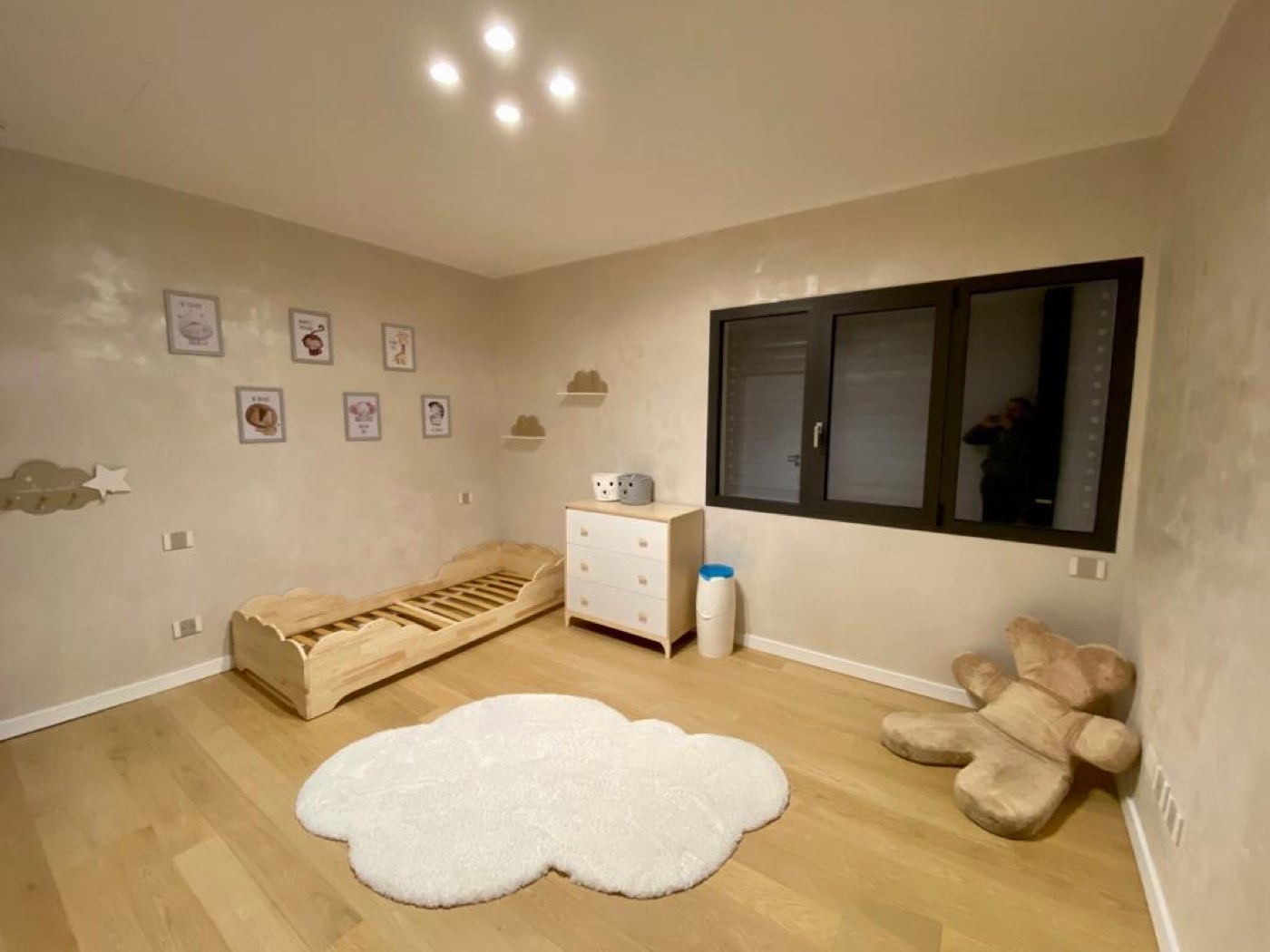 Cameretta per bambini con pavimento in rovere chiaro e tappeto a forma di nuvola