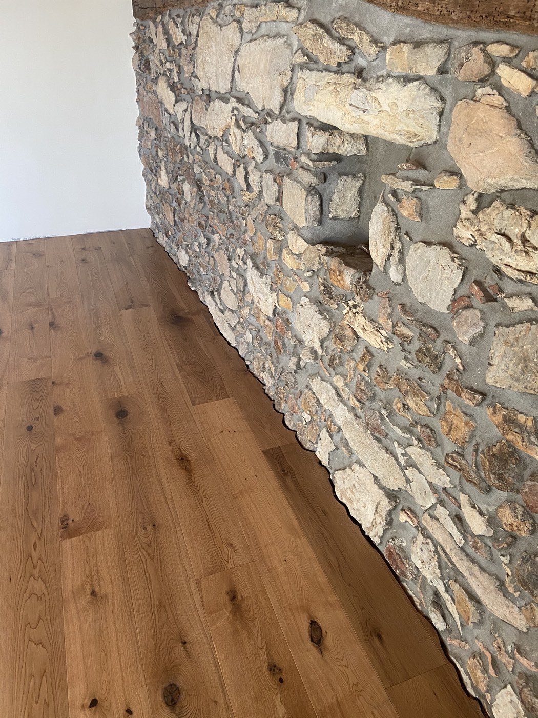 Pavimento in rovere a contatto con un muro in pietra a vista in una casa di campagna ristrutturata